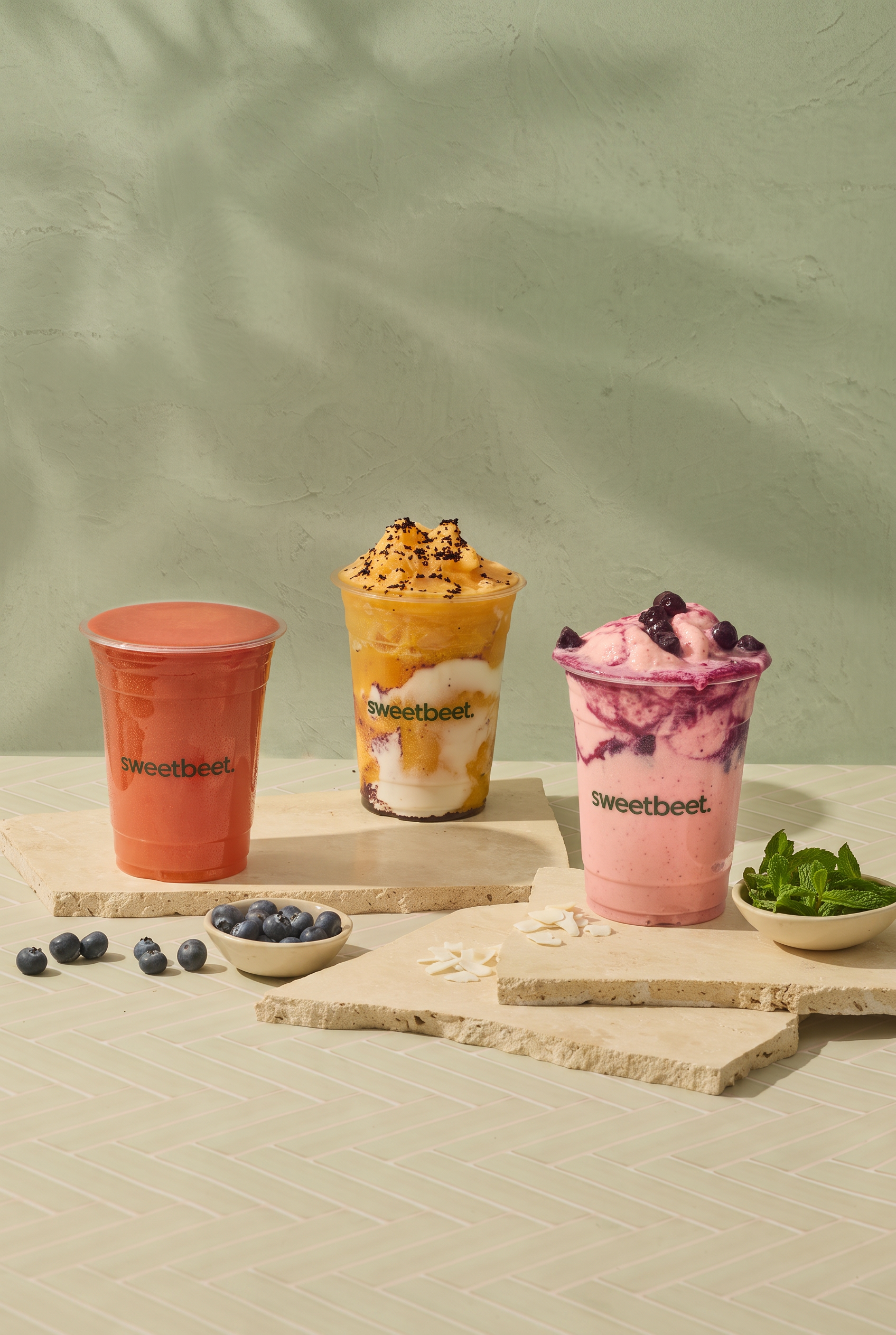 Three Sweetbeet smoothies in pink, green and orange