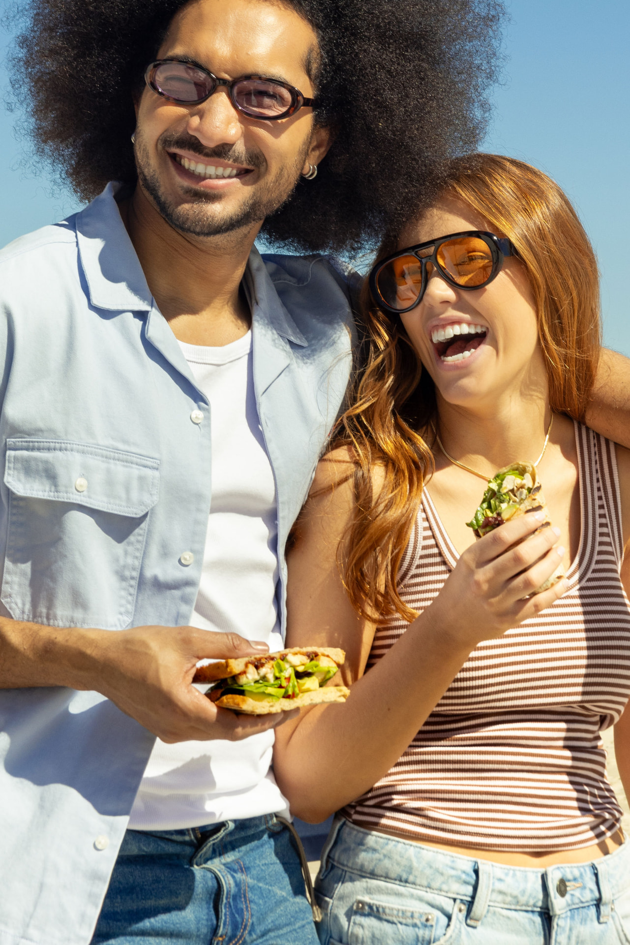 Two friends laughing with Sweetbeet wraps in hand